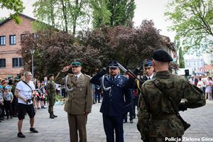 Oddanie honorów podczas skłaniania kwiatów pod pomnikiem przez służby mundurowe .