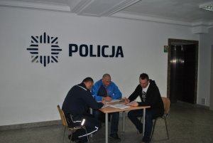 Policjant w towarzystwie dwóch mężczyzn przy stole