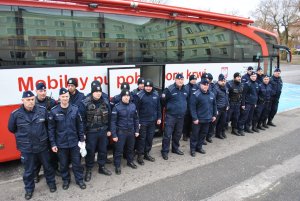 Policjanci w dwuszeregu przed autobusem do pobrań krwi