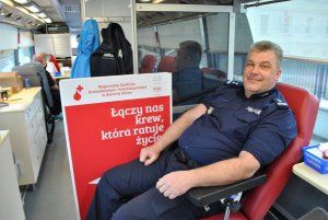 Uśmiechnięty policjant na fotelu przed oddaniem krwi