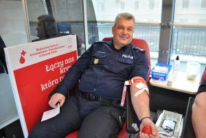 Zadowolony policjant siedzący na fotelu podczas poboru krwi