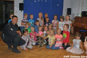 Uśmiechnięty policjant z grupa przedszkolaków
