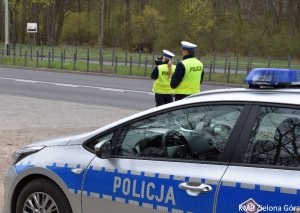 fotografia kolorowa, patrol policyjny kontroluje prędkość pojazdów przy użyciu laserowego miernika