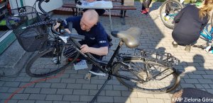 fotografia kolorowa, policjant znakuje rower