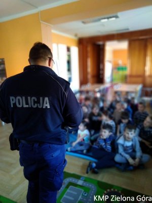 zdjęcie kolorowe, policjant stojący tyłem do obiektywu na spotkaniu z dziećmi