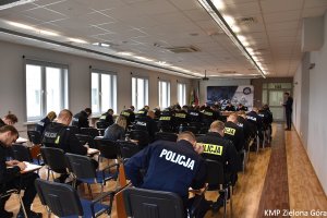 Zdjęcie kolorowe. Policjanci siedzą przy stolikach i rozwiązują test