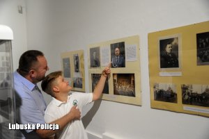 Ojciec i syn oglądający zdjęcia policjantów wywieszonych na ścianie