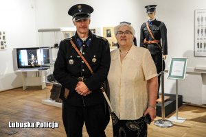 Policjant ubrany w stary mundur pozujący do zdjęcia ze starszą Panią