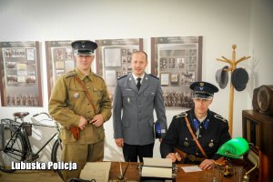 Zdjęcie trzech policjantów. Dwóch ubranych w stare mundury, a jeden po środku ubrany w nowy mundur