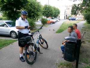 Policjant legitymujący dwóch mężczyzn spożywających alkohol w miejscu publicznym