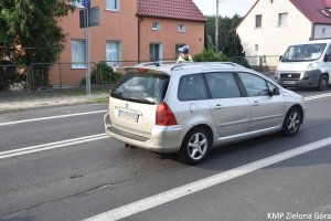 Zdjęcie policjanta sprawdzającego alkomatem trzeźwość kierowcy siedzącego w aucie