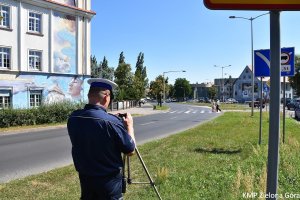 Policjant wykonujący zdjęcie przejścia dla pieszych na pasie zieleni