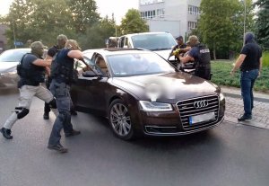 Sześciu zamaskowanych policjantów z bronią skierowaną w stronę zatrzymanego samochodu