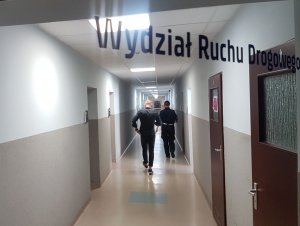 Policjantka i mężczyzna idą korytarzem w Komendzie