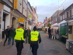 Dwóch policjantów spaceruje i pilnuje bezpieczeństwa na deptaku podczas winobrania