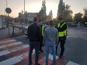 Dwóch policjantów rozmawia z dwoma mężczyznami