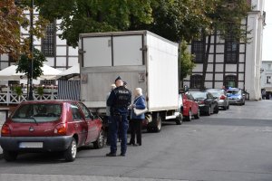 Policjant spisuje nieprawidłowo zaparkowany samochód