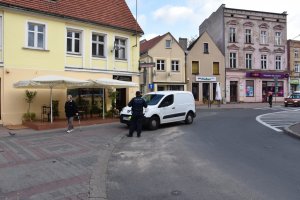 Policjant stoi przy nieprawidłowo zaparkowanym samochodzie