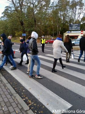 Policjantka Ruchu Drogowego wstrzymuje ruch żeby piesi mogli przejść przez przejście dla pieszych