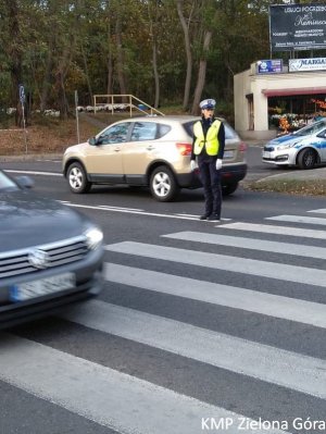 Policjantka Ruchu Drogowego kieruje ruchem na drodze przy cmentarzu