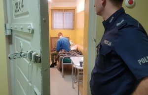 Policjant obserwuje zatrzymanego mężczyznę w celi