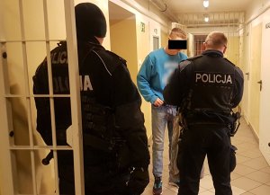 Dwóch policjantów zakuwa zatrzymanego mężczyznę