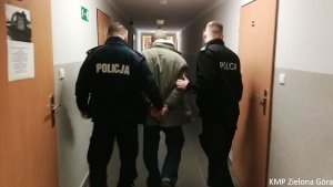 Policjanci prowadza mężczyznę w kajdankach