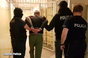 Policjanci prowadzący mężczyznę w kajdankach