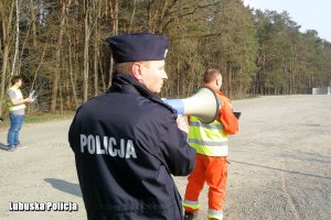 Policjant mówiący przez megafon.