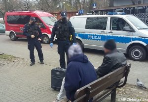 Policjanci przy rozmowie z zielonogórskimi bezdomnymi na tle radiowozu