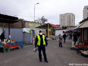 Policjant w mundurze z megafonem na tle targowiska