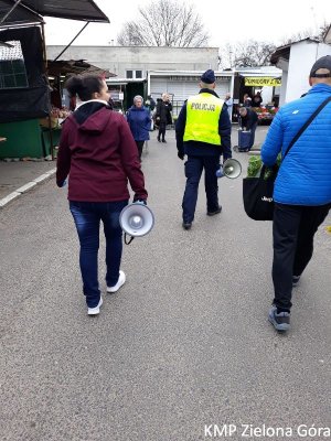 Policjant wraz z przechodniami idący z megafonem