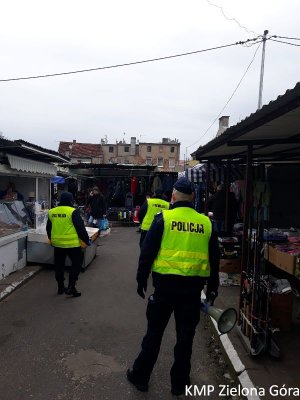 Policjanci w odblaskowych kamizelkach na tle targowiska