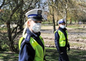 Policjanci przybrani w maseczki ochronne.