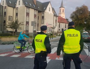 Policjanci w kamizelkach odblaskowych przy przejściu dla pieszych .