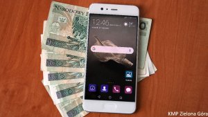 Zdjęcie przedstawia telefon i pięć banknotów stu złotowych