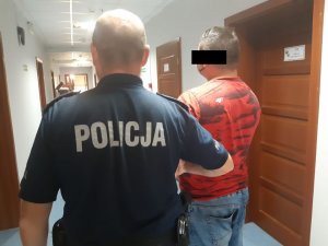 Policjant trzyma zatrzymanego mężczyznę