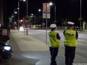 Policjanci stoją przy drodze i obserwują jadący pojazd