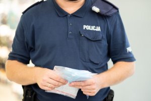 Policjant trzymający w rękach maseczki do rozdania