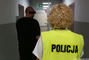 Policjantka w kamizelce odblaskowej prowadząca sprawcę wypadku.