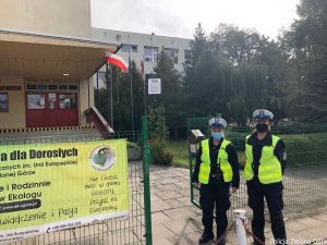 Policjantki w kamizelkach odblaskowych przed szkołą.