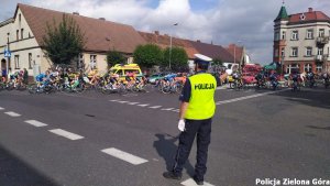 Policjant w kamizelce odblaskowej kierujący ruchem, podczas zawodów kolarskich.