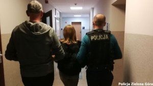 Kobieta w blond włosach prowadzona przez policjantów.