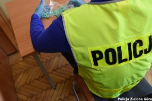 Policjant w kamizelce odblaskowej sprawdzający ilość skonfiskowanych narkotyków.