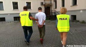 Policjanci w kamizelkach odblaskowych odprowadzający dealera narkotykowego.