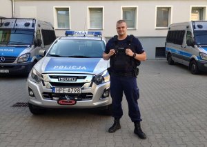 Policjant stoi przy radiowozie