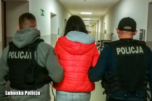 Policjanci prowadzą zatrzymaną kobietę