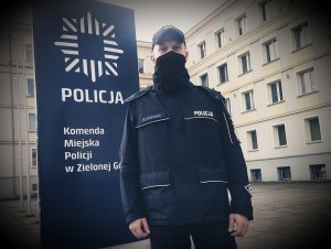 Policjant w maseczce stoi przed Komendą