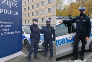 Policjanci stojący obok radiowozów