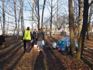 Policjanci przy osobie bezdomnej mieszkającej w namiocie w parku